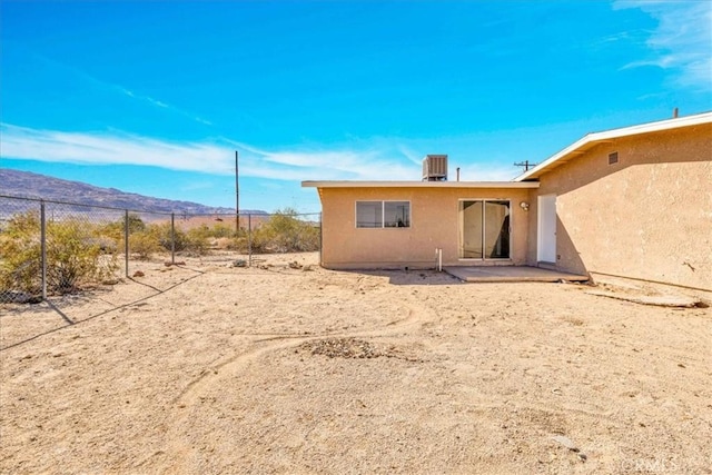 back of property featuring fence, central AC, stucco siding, a patio area, and a mountain view