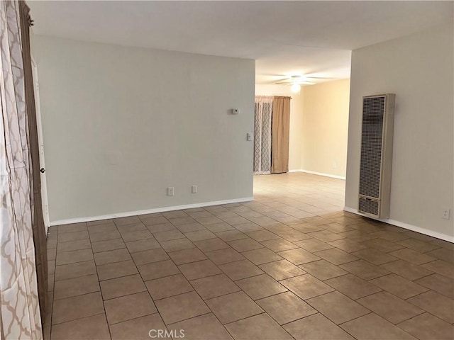 spare room with baseboards, a heating unit, and a ceiling fan