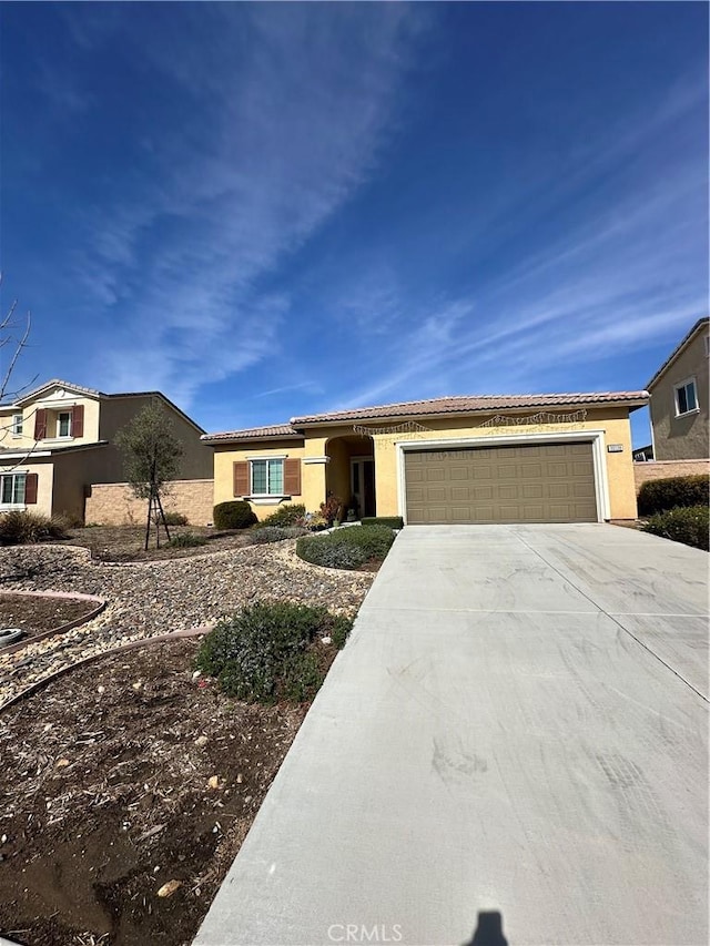 view of front of home with a garage, driveway, a tiled roof, and stucco siding