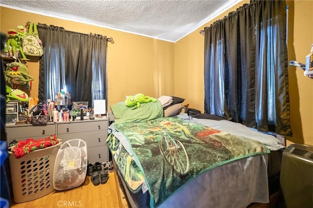 bedroom featuring ornamental molding, a textured ceiling, and wood finished floors