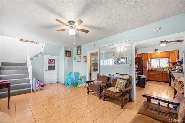 living area with light tile patterned flooring, stairs, and a ceiling fan