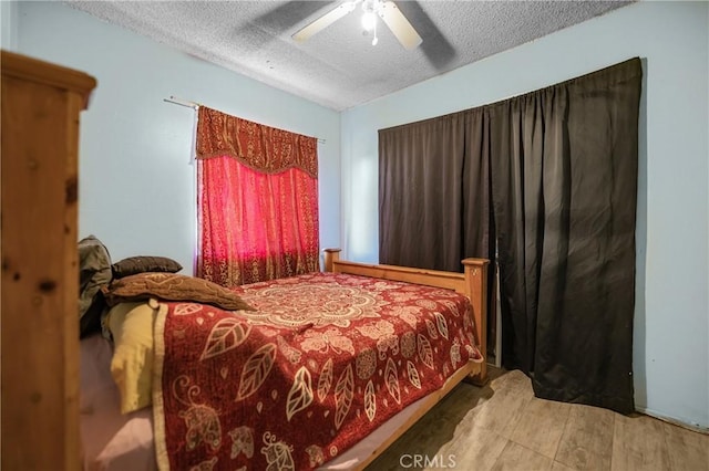 bedroom featuring a ceiling fan, wood finished floors, and a textured ceiling