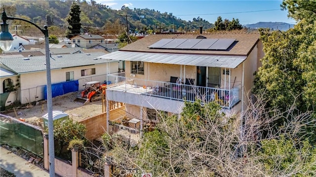 back of house featuring a fenced backyard, solar panels, roof with shingles, and stucco siding