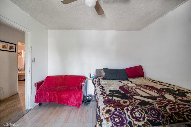 bedroom featuring a ceiling fan, wood finished floors, and a textured ceiling