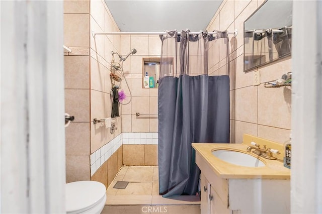 bathroom featuring toilet, tile walls, vanity, and a tile shower