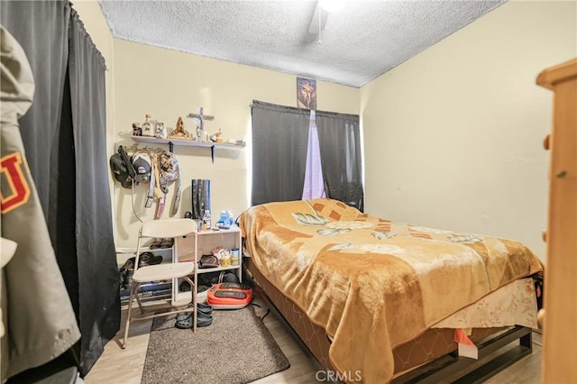 bedroom with a textured ceiling, ceiling fan, and wood finished floors