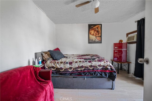 bedroom with ceiling fan, wood finished floors, and a textured ceiling