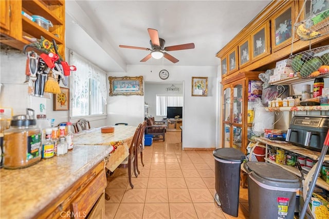 kitchen with glass insert cabinets, baseboards, ceiling fan, light countertops, and light tile patterned floors