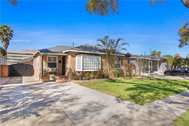 ranch-style home featuring a front yard, a gate, and stucco siding