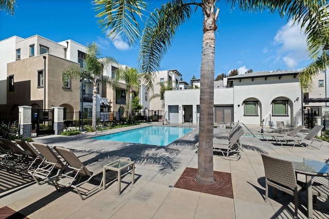 community pool featuring a patio area, fence, and a residential view