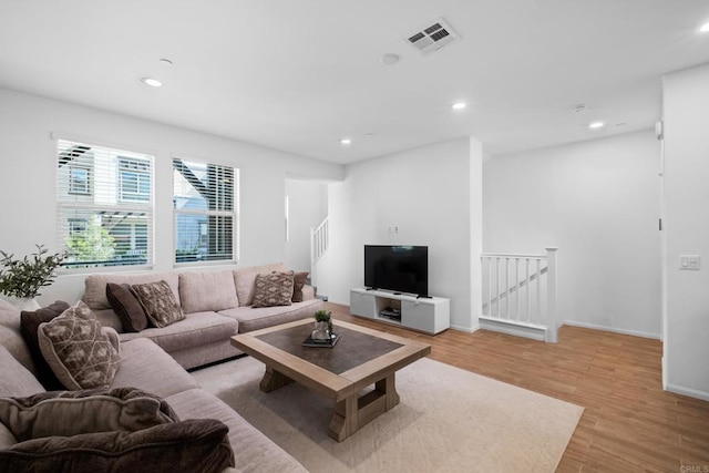 living area with recessed lighting, visible vents, light wood-style flooring, and baseboards