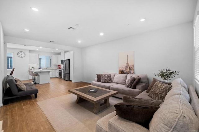 living room featuring light wood-type flooring, visible vents, and recessed lighting