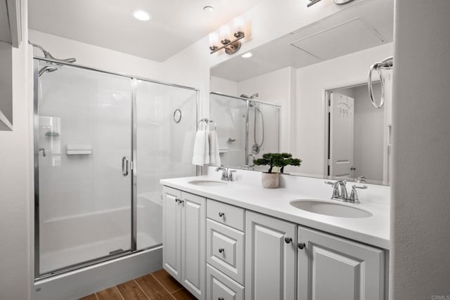 bathroom featuring a stall shower, double vanity, a sink, and wood finished floors