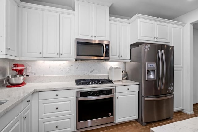 kitchen with white cabinets, stainless steel appliances, decorative backsplash, and wood finish floors