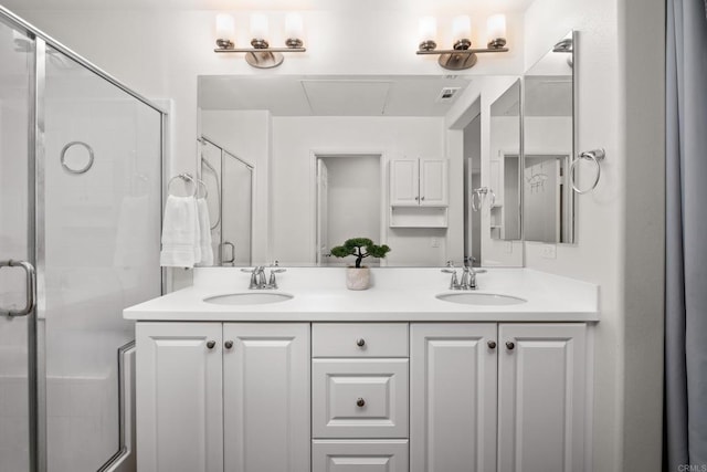 bathroom with double vanity, a shower stall, and a sink