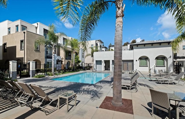 community pool with a patio area and fence