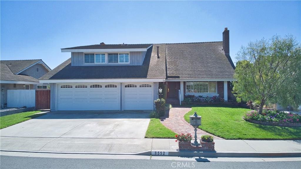 view of front of house with an attached garage, fence, concrete driveway, and a front yard