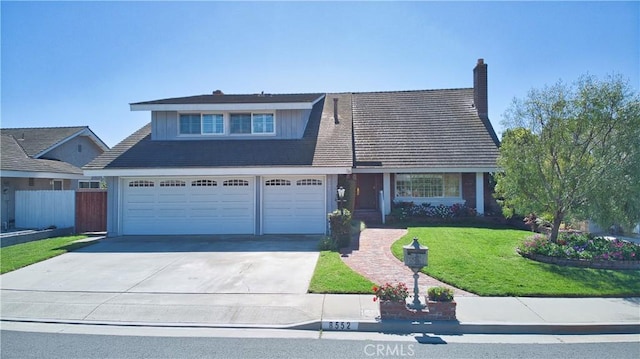 view of front of house with an attached garage, fence, concrete driveway, and a front yard