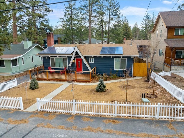 view of front of house with a fenced front yard, a chimney, a gate, and roof mounted solar panels