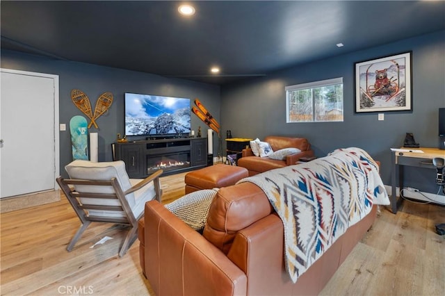 home theater room featuring a glass covered fireplace, recessed lighting, and wood finished floors