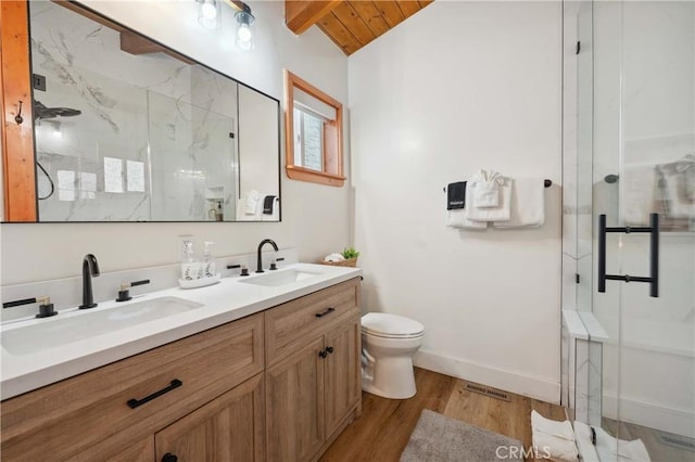 bathroom with toilet, a stall shower, a sink, and wood finished floors