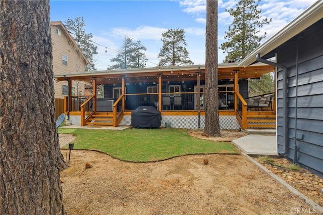 rear view of house with a lawn and a wooden deck