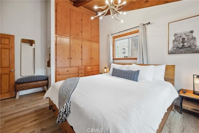 bedroom with a chandelier, wood finished floors, and beam ceiling