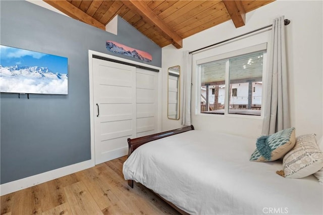 bedroom with baseboards, wooden ceiling, light wood-style flooring, vaulted ceiling with beams, and a closet