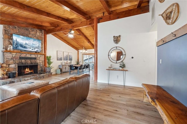 living area featuring high vaulted ceiling, light wood-style flooring, a fireplace, wood ceiling, and beam ceiling