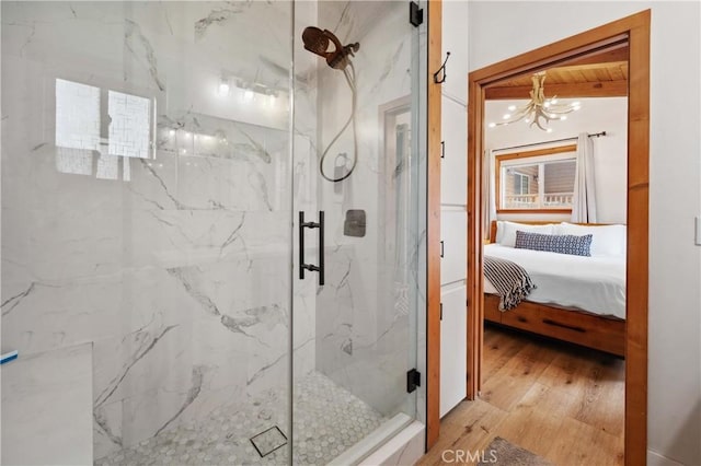 full bath featuring wood-type flooring, a marble finish shower, a notable chandelier, and ensuite bathroom