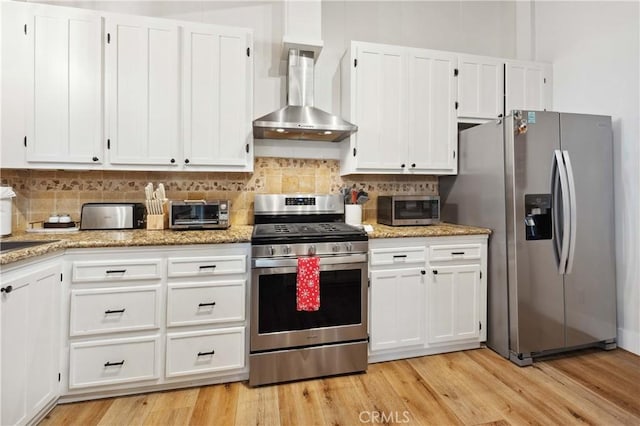 kitchen with white cabinetry, wall chimney exhaust hood, appliances with stainless steel finishes, and backsplash