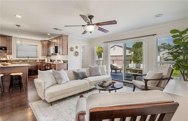 living area featuring recessed lighting, dark wood-type flooring, visible vents, a ceiling fan, and ornamental molding