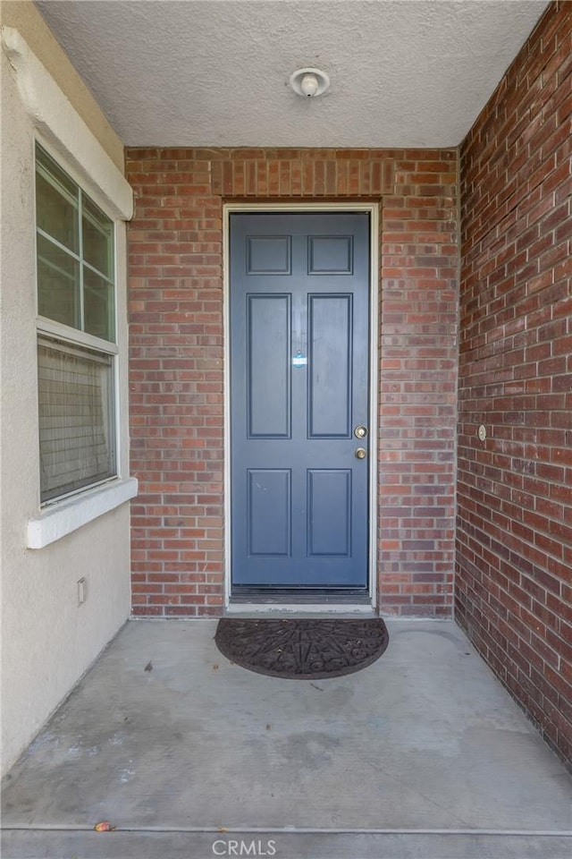 view of exterior entry featuring brick siding