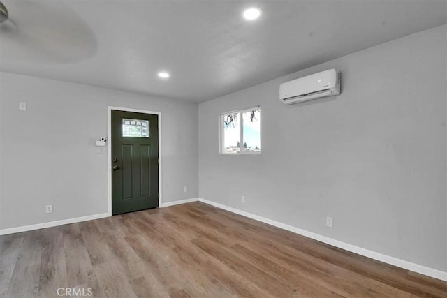 entrance foyer featuring recessed lighting, a wall unit AC, wood finished floors, and baseboards