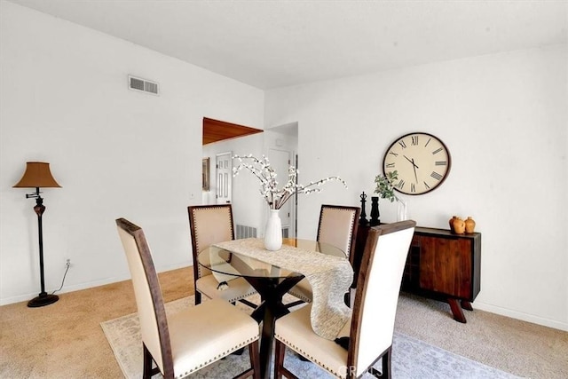 dining room with lofted ceiling, visible vents, light carpet, and baseboards