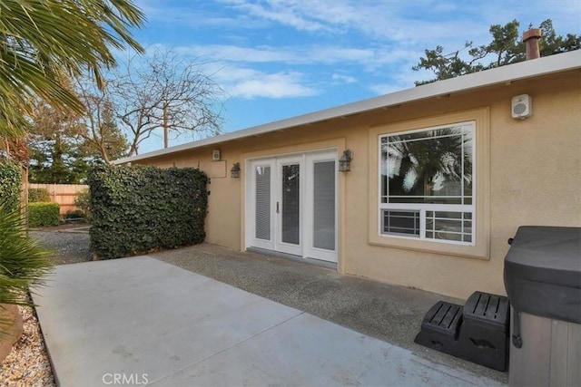 rear view of house featuring french doors, a patio, fence, and stucco siding