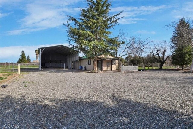 view of outbuilding with driveway, a carport, and fence