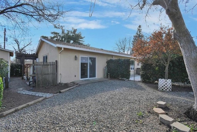 rear view of property featuring fence and stucco siding