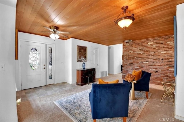 foyer entrance with wooden ceiling, brick wall, visible vents, and a ceiling fan