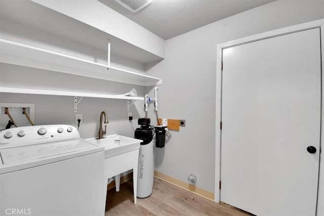 clothes washing area with light wood-type flooring, washer / clothes dryer, visible vents, and laundry area