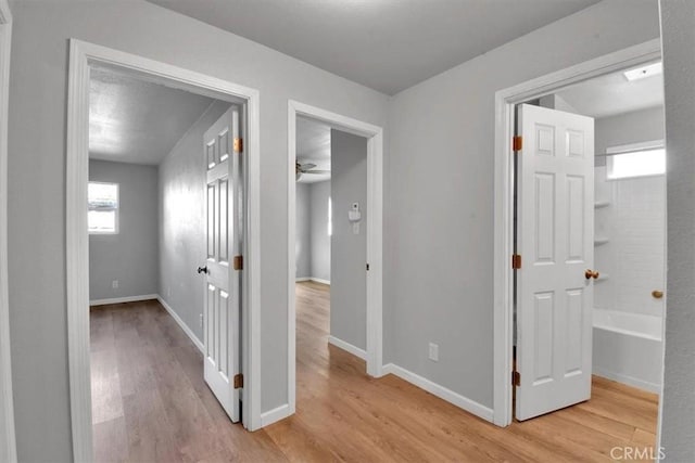 hall with light wood-style flooring and baseboards