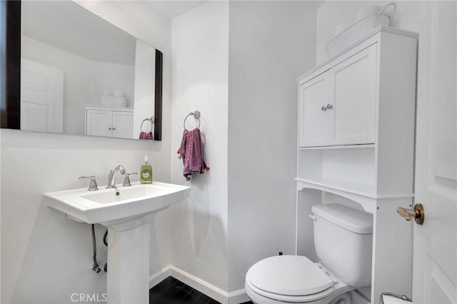 bathroom with wood finished floors, toilet, and baseboards