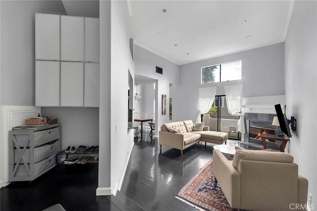 living room with visible vents, a premium fireplace, a high ceiling, and baseboards