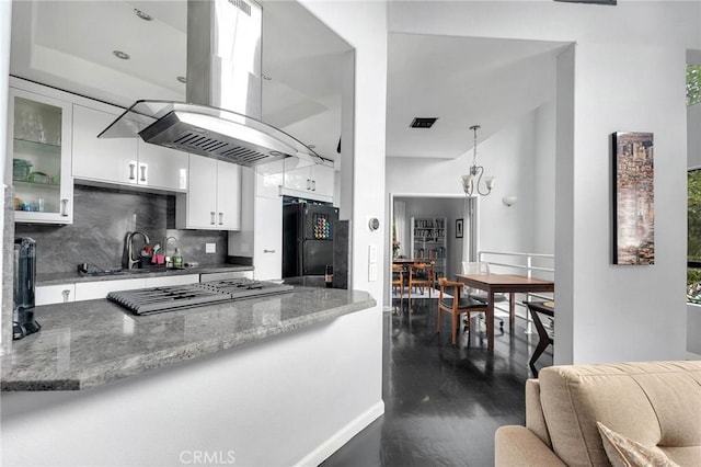 kitchen with island range hood, a sink, white cabinetry, backsplash, and freestanding refrigerator