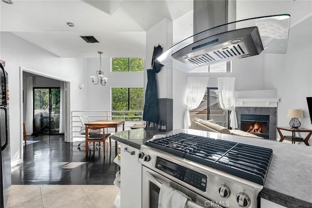 kitchen featuring a healthy amount of sunlight, stainless steel gas range, an inviting chandelier, and a high end fireplace