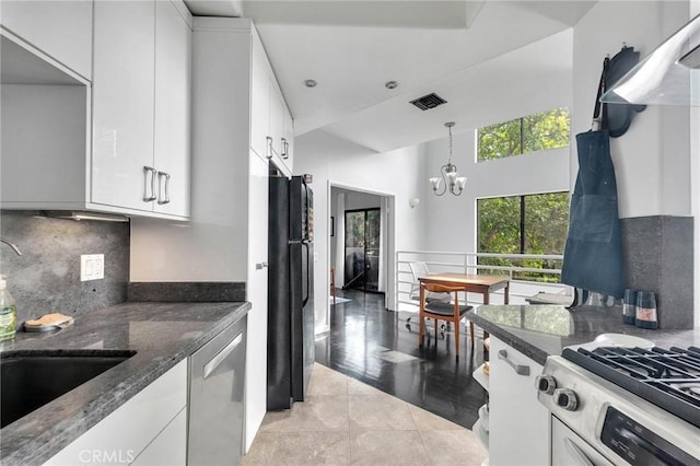 kitchen featuring visible vents, stainless steel dishwasher, freestanding refrigerator, white cabinets, and gas range