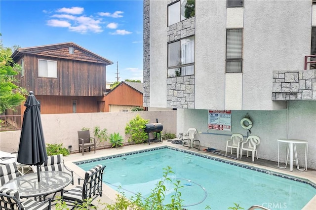 view of swimming pool featuring a patio area, area for grilling, and fence