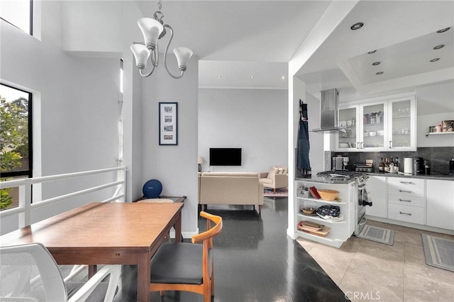 kitchen with backsplash, white cabinets, wall chimney range hood, and open shelves