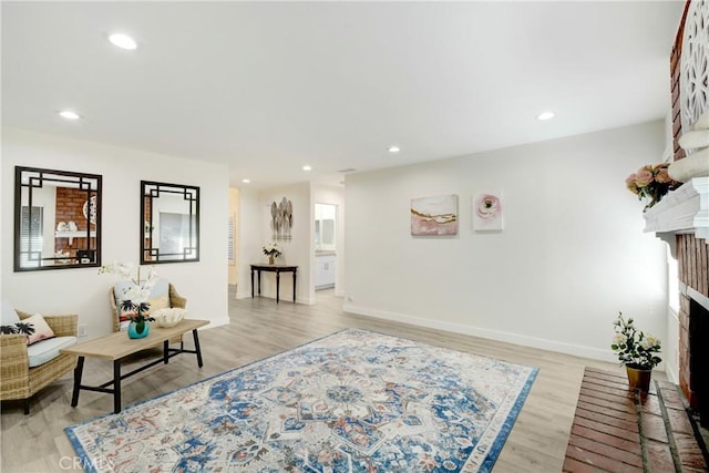 living room with baseboards, a brick fireplace, light wood-style flooring, and recessed lighting