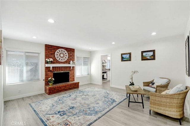 living room with light wood-type flooring, a brick fireplace, baseboards, and recessed lighting